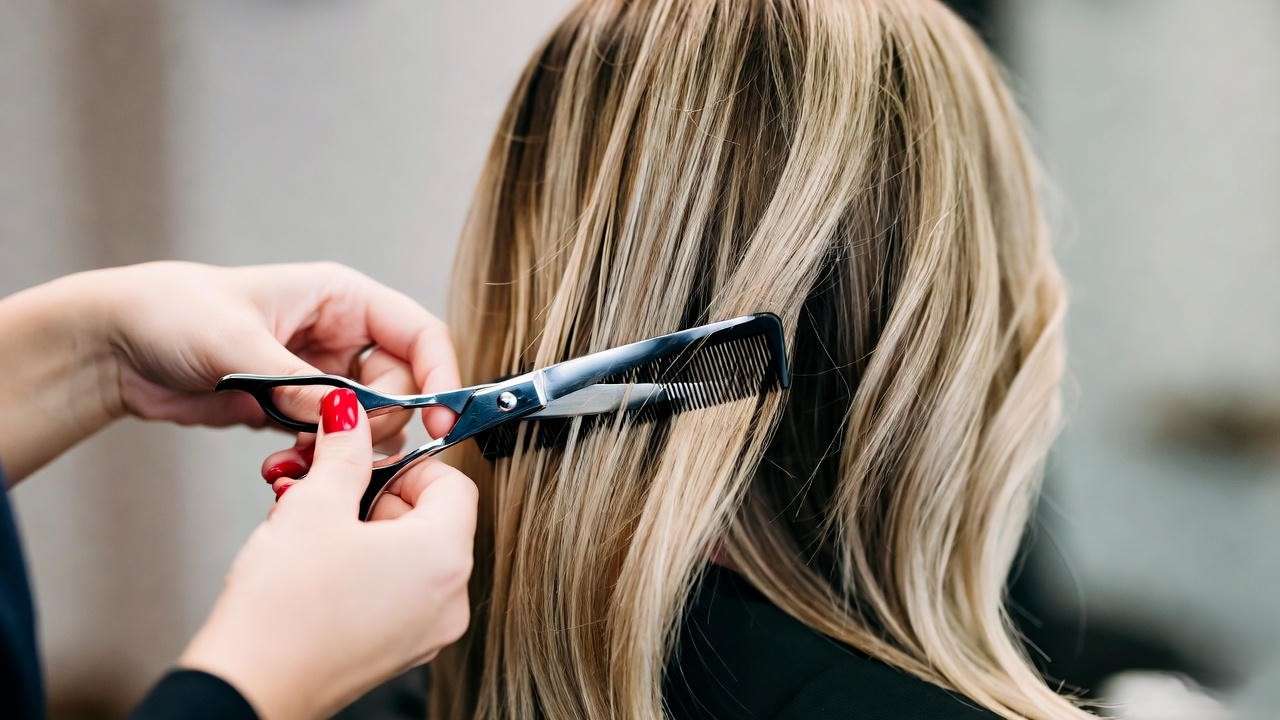 Hairstylist creating the iconic Rachel haircut with scissors and comb, 90s Friends style.
